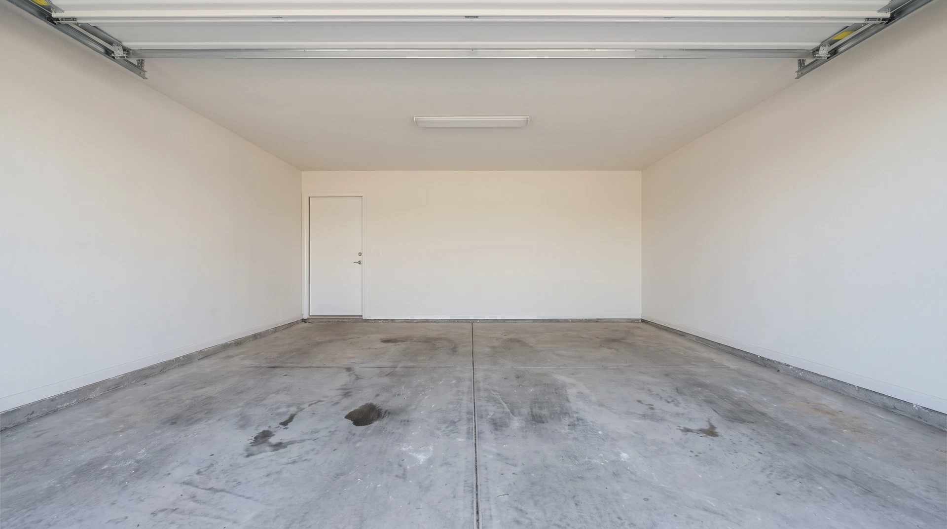 Bare stained concrete floor in a residential double garage before epoxy coating in Chilliwack, BC